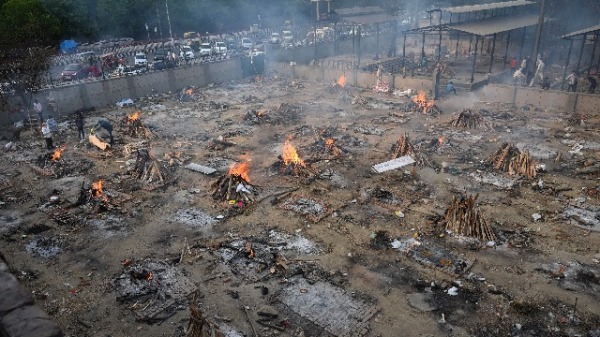 图为4月26日，印度民众在空旷地方焚烧染疫死亡者的尸体