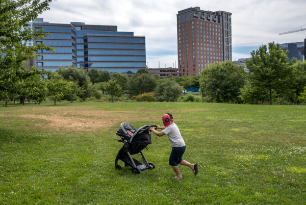 2020年大瘟疫期间，美国人口出生率和生育率都下降到百年来的最低水平。图为2020年6月在康涅狄格州某地，一个7岁的小哥哥在草地上推着他10个星期大的小弟弟的婴儿车。（图片来源：John Moore/Getty Images）