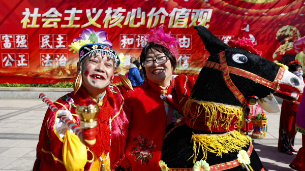 2021年4月28日，北京一处公园里，人们在巨幅“社会主义核心价值观”的标语前舞秧歌。