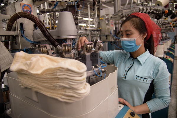 2021年5月24日，一名女工在朝鲜平壤袜厂生产线上工作。