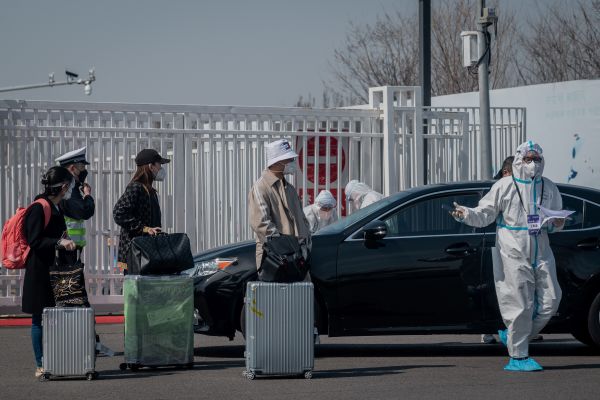 幾名旅客在工作人員帶領下，正走入北京一個隔離點