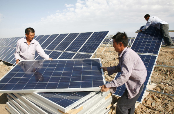 圖為2011年8月22日，中國新疆哈密市，建築工人在哈密太陽能發電站安裝太陽能板。 