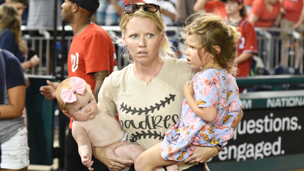 华盛顿特区的国民体育场举行的棒球比赛中，在听到枪声后，惊恐的妈妈球迷抱着两个孩子