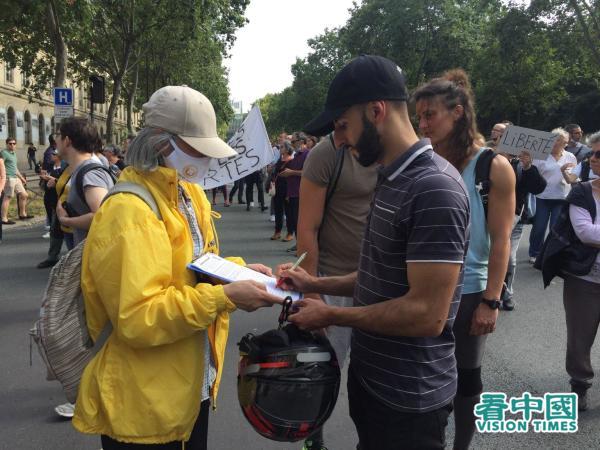 路过集会附近的法国民众签署反迫害请愿书