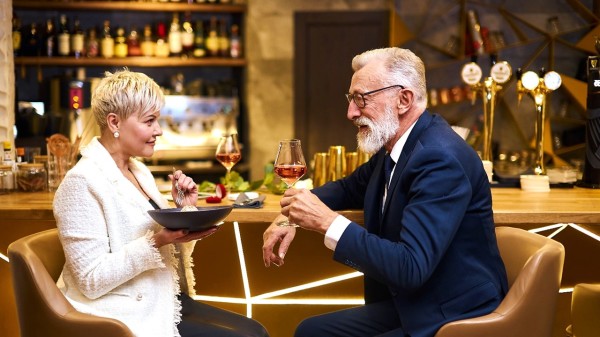 一个老人和一个女人在一间餐厅吃饭喝酒