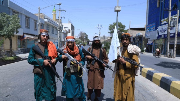 在军事接管阿富汗的过程中，几名塔利班成员在阿舒拉游行现场附近道路上。