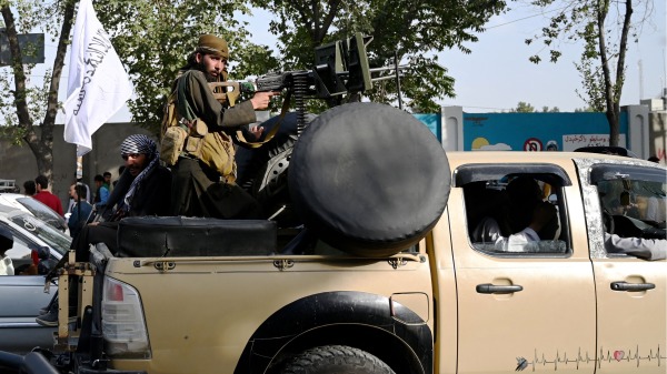 在军事接管阿富汗喀布尔后，塔利班成员站在一辆装有重机枪的皮卡车上巡逻。