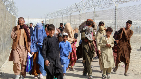 图为2021 年 8 月 25 日，在塔利班军事接管阿富汗之后，阿富汗难民在位于查曼的巴基斯坦 - 阿富汗边境过境点进入巴基斯坦时，走进一条铁丝网包围的走廊