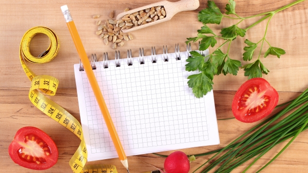 新鲜希腊沙拉配蔬菜、厘米和记事本，用于写笔记、健康营养和减肥概念