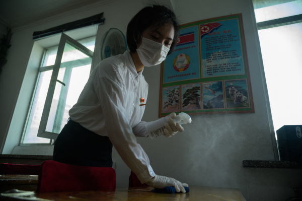 2021年8月11日，作为针对Covid-19的预防措施的一部分，朝鲜平壤商业大学的一名学生在教室里喷洒消毒剂。