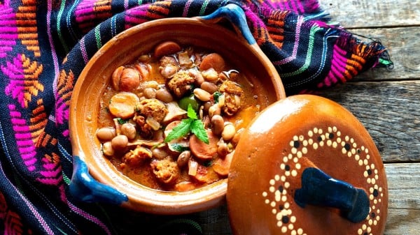 墨西哥豆被称为“charros”，木制背景上有香肠和培根