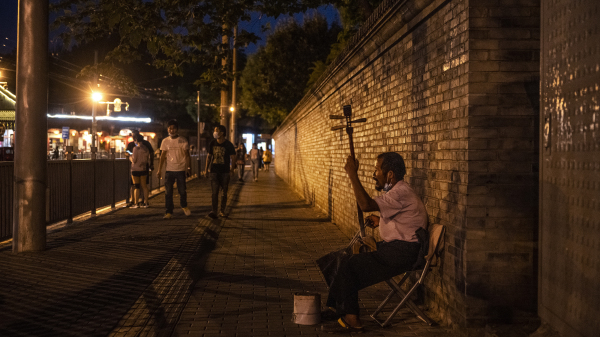 2021年8月24日的北京，一名男子在购物区的街道上卖艺求生。