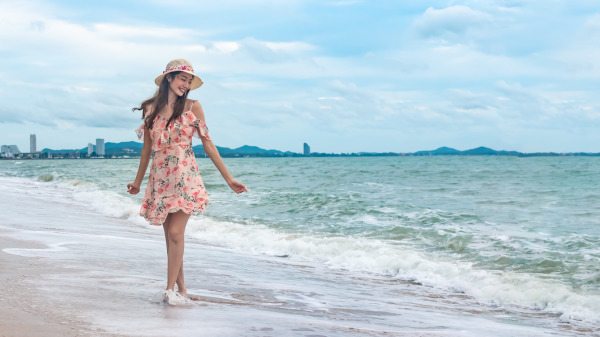 女人开心戴着帽子在海边