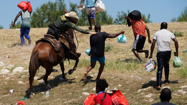 一名騎馬的美國邊境巡邏人員試圖阻止一名海地非法移民進入位於德克薩斯州阿庫納德爾里奧國際大橋附近的、格蘭德河岸邊的營地。