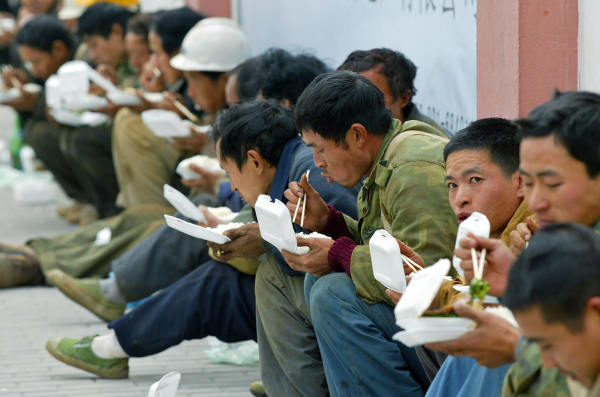 来自西南省份四川的农民工在上海一处建筑工地附近吃午饭。