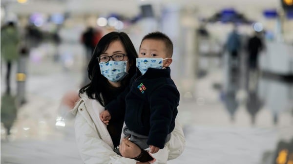 2020年1月21日，一名戴着防护口罩的妇女和儿童走向北京大兴国际机场的登机柜台。
