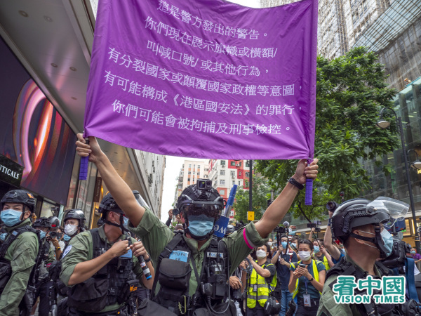 有市民喊出「光復香港 時代革命」口號，警察馬上舉起紫旗警告其違反《港區國安法》。（圖片來源：龐大衛/看中國）