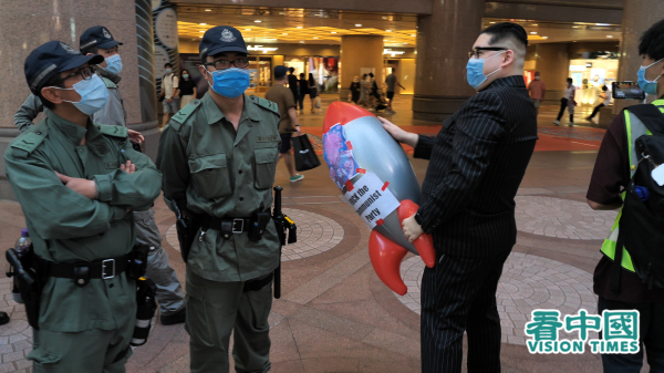 擅長飾演北韓領導人金正恩的Howard X，向港警舉起印有「習病毒」的道具飛彈。（圖片來源：龐大衛/看中國）
