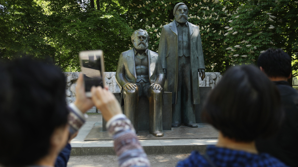 2018年5月4日，幾個中國遊客在柏林一處公園裡的馬克思和恩格斯雕像處拍照。（圖片來源：Sean GallupGetty Images)