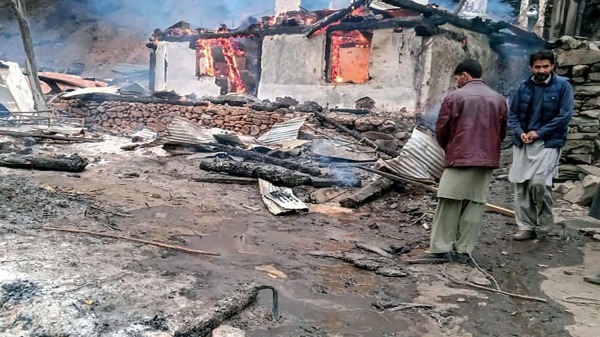 2020年11月13日，在巴基斯坦控制的克什米尔尼勒河谷，当地居民站在燃烧的房屋旁。