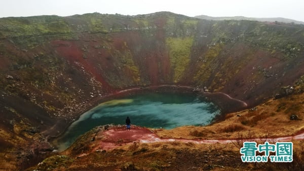 曾經的火山口已經變成翠綠湖泊，而湖泊四圍是赤紅的泥土。（圖片來源：作者提供）