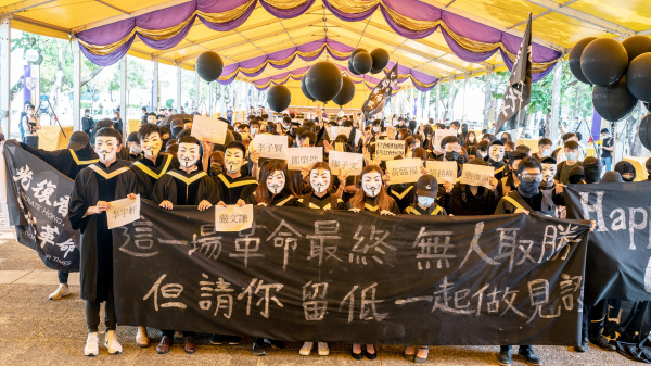 應屆中大畢業生穿上畢業袍、手持「光復香港 時代革命」等橫幅在校內遊行，又在原定畢業禮地點合唱《願榮光歸香港》。（圖片來源：Anthony Kwan/Getty Images）