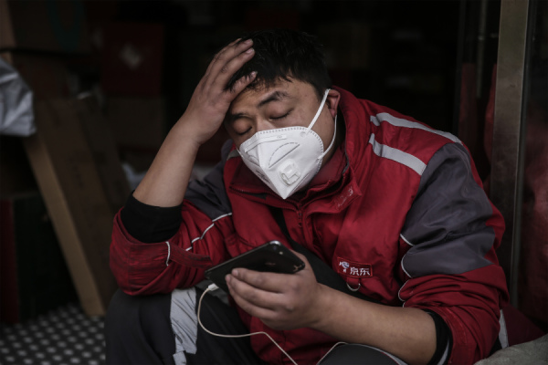 2020年1月29日，一個戴著口罩的快遞員在湖北省武漢市的特快車站休息。