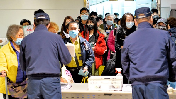 防疫人員在台北桃園機場空橋門口收取旅客入境健康聲明卡。