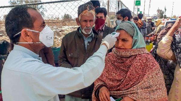 2020年2月29日，一名工作人员检查从伊朗经巴基斯坦与伊朗边境小镇塔夫坦（Taftan）返回伊朗的朝圣者的体温
