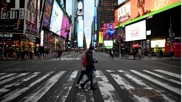 3月17日，民众戴口罩横过纽约时代广场。（图片来源：JOHANNES EISELE/AFP/Getty Images）