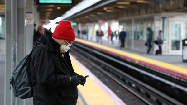 2020年3月18日，一名戴口罩的男子在人潮稀少的紐約牙買加火車站上候車。（圖片來源：Al Bello/Getty Images）