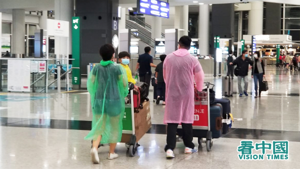 3月23日，一名負責機場檢疫的衛生署女醫生確診中共肺炎。圖為入境香港旅客穿上雨衣防感染。（圖片來源：萊恩/看中國）