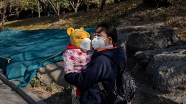 北京街道邊的一位戴口罩的婦女和一名兒童