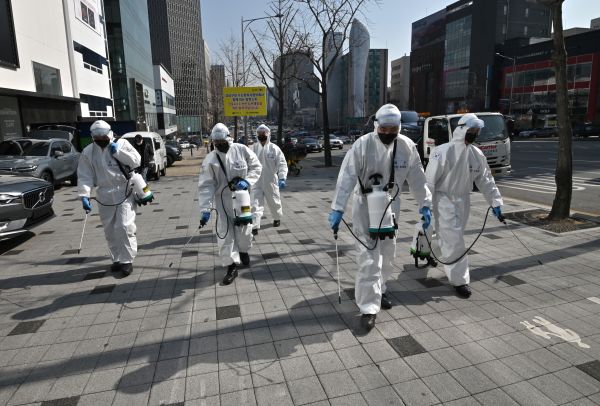 韩国士兵在街上穿着防护装备喷雾消毒剂