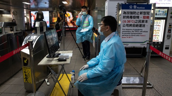 2020年3月19日台北捷運職員用一台熱掃描儀監視乘客的溫度。（图片来源：Paula Bronstein/Getty Images）