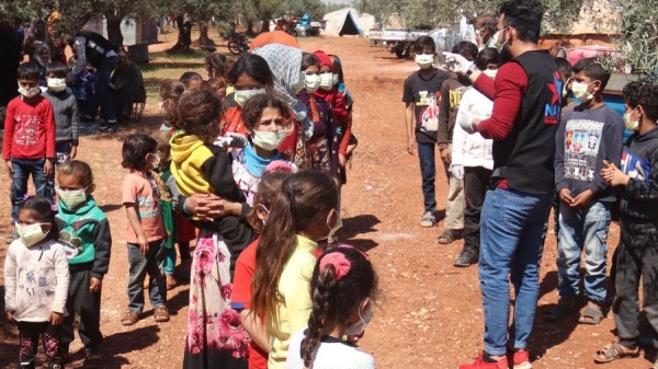 2020年4月14日，叙利亚伊德利布省北部农村哈扎诺镇附近的難民營地的兒童，听讲解防止中共病毒传播的保护措施