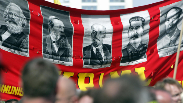 2005年5月1日在德国柏林亚历山大广场举行的“五一劳动节”游行中，示威者展示了一条横幅，展示共产主义的发源者和它的壮大者：马克思，恩格斯，列宁，斯大林和毛泽东。（图片来源：JOHN MACDOUGALLAFP via Getty Images）(16:9)