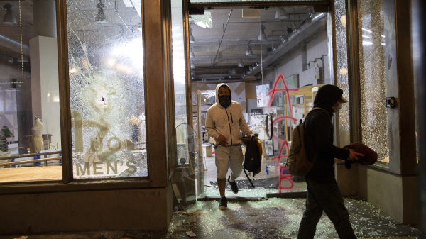 2020年5月30日晚，抢劫者从西雅图的一家被砸碎门面的商店中走出来。 早些时候抗议者们在此举行了一次和平集会，抗议警察过度执法导致乔治·弗洛伊德（George Floyd）的死去。（图片来源：Karen Ducey / Getty Images）