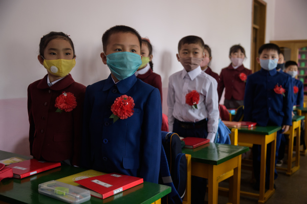 2020年6月3日，北韩学校重新开放后，孩童戴口罩别着鲜红胸花回到教室上课。