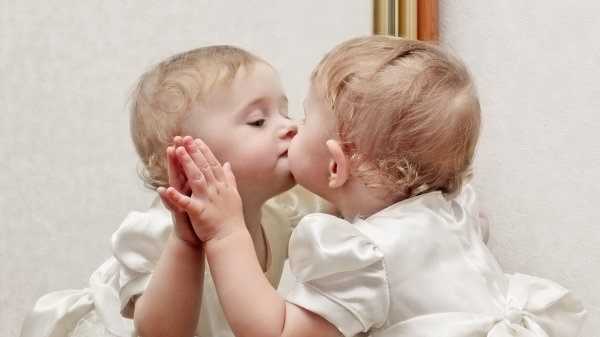 孩子亲吻镜子中的自己