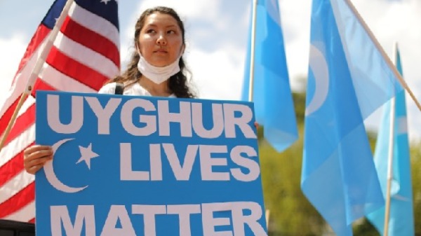 白宮外一個女士手舉著「維吾爾人的命也是命」的標語牌