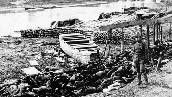 秦淮河岸边大屠杀遇难者的尸体，旁边站着一名日本士兵。