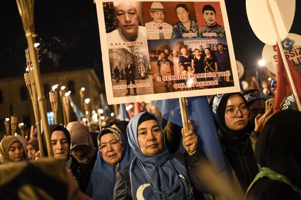 中国维吾尔穆斯林在伊斯坦布尔法提赫举行的示威活动中，手持火炬和据称在中国“再教育营”中丧生的人的标语牌。