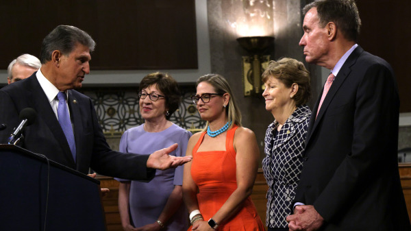 美国国会参议员乔．曼钦（Joe Manchin，左一）和参议员克里斯汀．希内玛（Kyrsten Sinema，左三穿橙红裙子者）在新闻发布会上