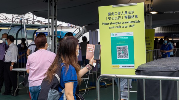 图为香港市民进入政府、餐厅等场所时，必须使用安心出行手机程式扫描二维码。（图片来源：Getty Images）