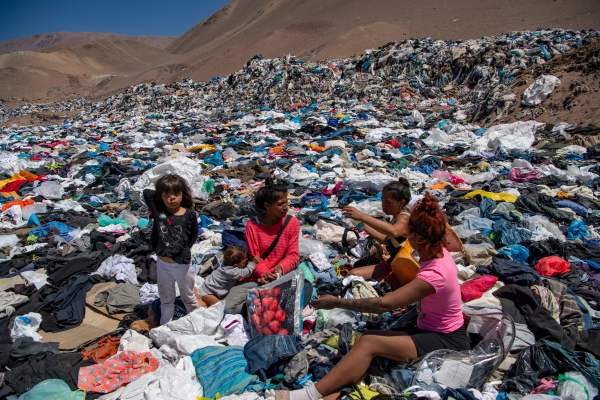 2021年9月26日，在智利阿塔卡馬沙漠中，幾個婦女在大量廢棄的舊衣服中尋找可以穿的衣服。