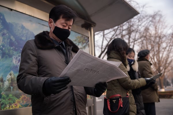 2021年1月21日，朝鲜平壤的一个公交车站上，一名男子在阅读官方报纸。