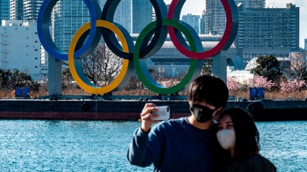 在2021年2月24日，一对情侣在东京台场海滨展出的奥运五环前摆姿势的照片。
