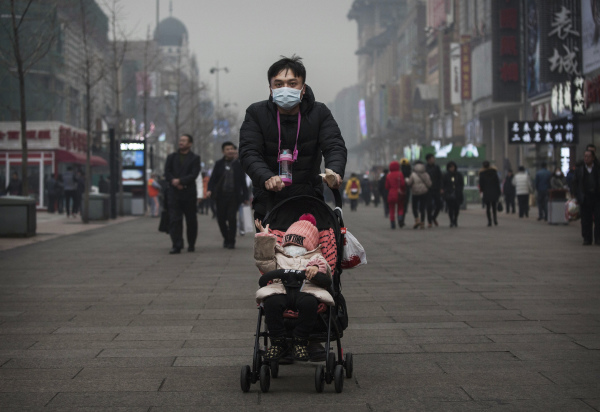 男子戴着口罩在北京街头推着小孩