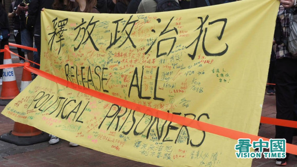 香港47名民主派被控“串谋颠覆国家政权”，法官苏惠德一度批准其中15人的保释申请，但律政司即时覆核，最终15人无法获释。图为场外市民拉横幅声援47人。（图片来源：李天正/看中国）